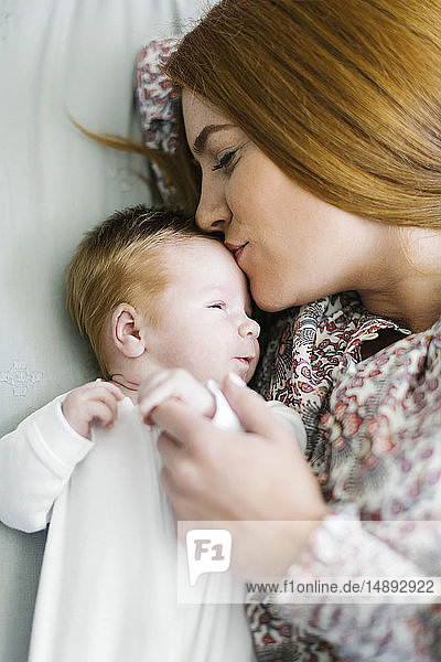Frau küsst den Kopf ihres neugeborenen Sohnes