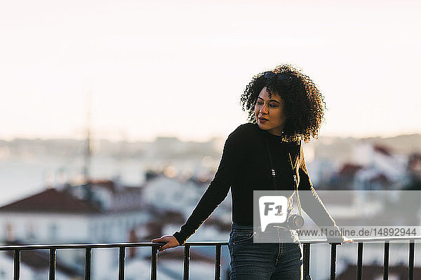 Young woman with camera leaning on railing