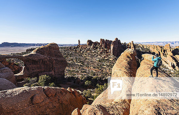 Woman taking photograph while hiking in Arches National Park  Utah  USA