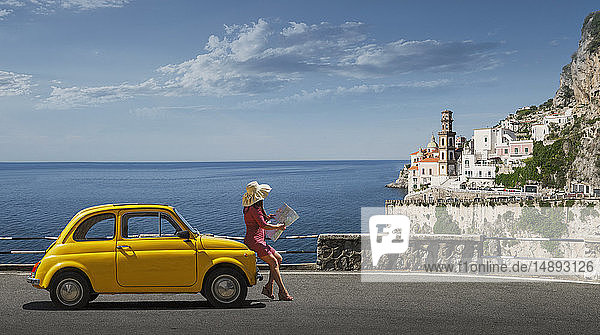 Frau mit Landkarte an gelbes Auto gelehnt in Atrani  Italien