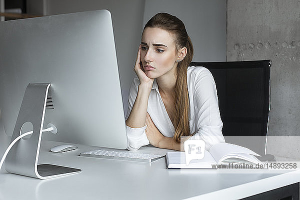 Depressive Geschäftsfrau  die an einem Desktop-Computer arbeitet