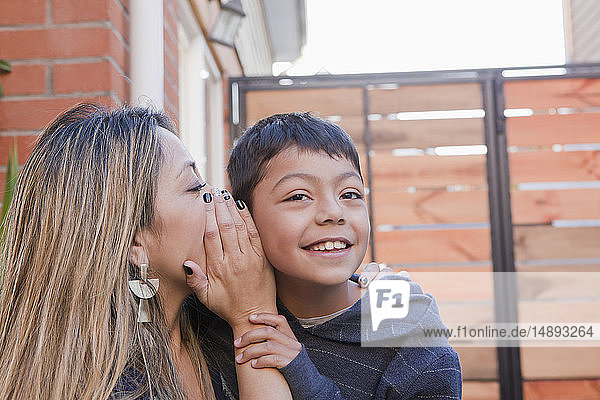 Mother whispering into her son's ear
