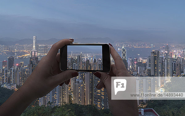 Hände einer Frau  die mit ihrem Smartphone eine Stadtlandschaft in Hongkong  China  fotografiert