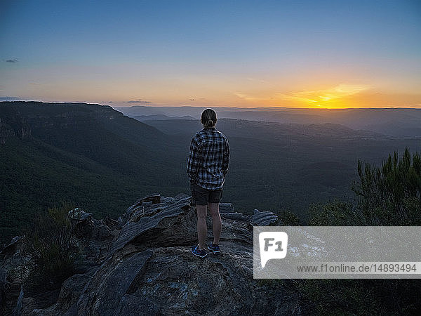 Woman standing on peak of Blue Mountains at sunrise in New South Wales  Australia