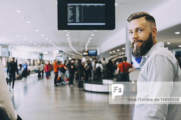 Porträt eines lächelnden Geschäftsmannes  der mit einer Geschäftsfrau am Flughafen steht