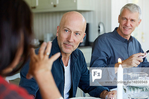 Mature men looking to female friend in dining room at home