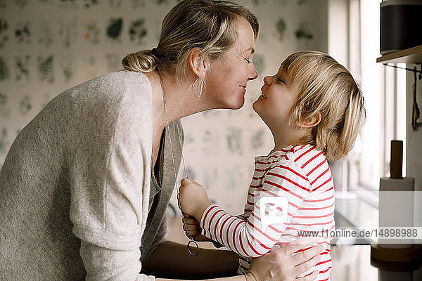 Seitenansicht einer spielerischen Mutter und Tochter  die zu Hause ihre Freizeit in der Küche verbringen