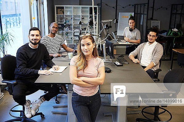 Porträt selbstbewusster Unternehmerinnen und Unternehmer am Schreibtisch im Kreativbüro