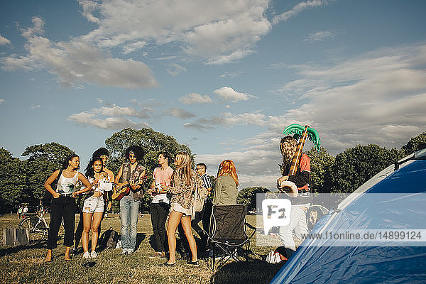 Multiethnische Freunde genießen Musik bei einer Veranstaltung gegen den Himmel an einem sonnigen Tag