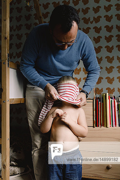 Father dressing daughter at home