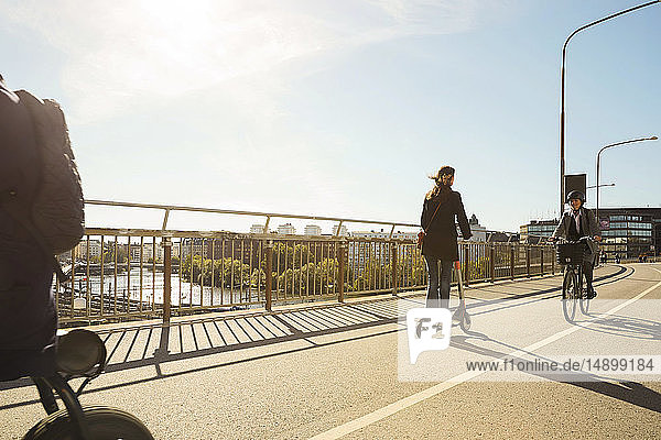 Pendler mit Elektrofahrzeugen auf Brücke gegen blauen Himmel