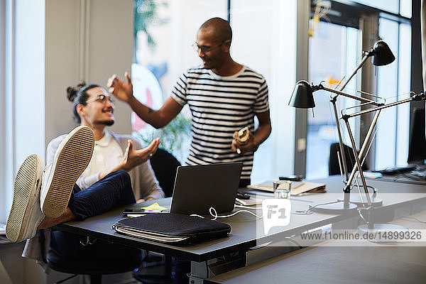 Creative businessmen greeting each other at desk in creative office