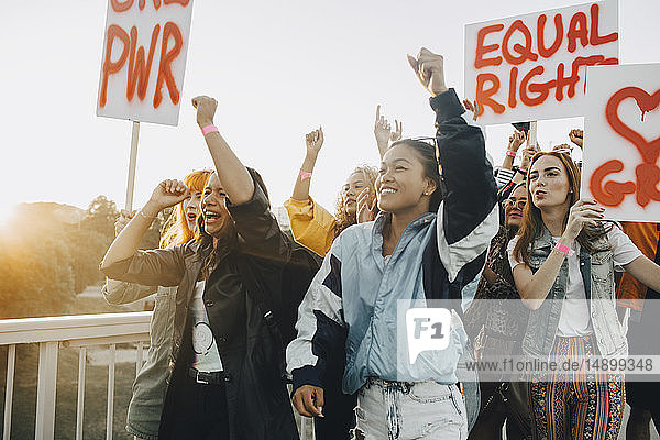 Young women shouting while protesting for equal rights against sky