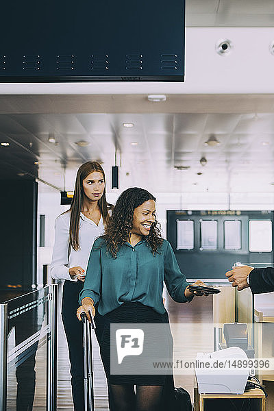 Multi-ethnic female colleagues going through check-in counter at airport