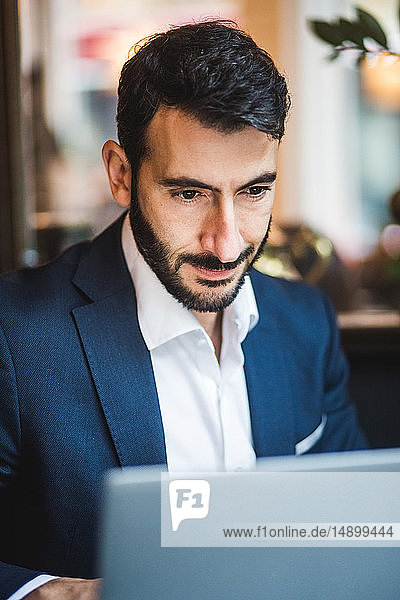 Selbstbewusster männlicher Unternehmer benutzt Laptop im Kreativbüro