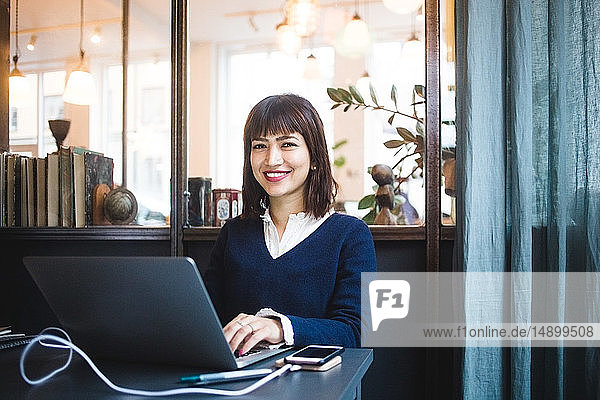 Porträt einer lächelnden Unternehmerin  die mit Laptop im Büro sitzt