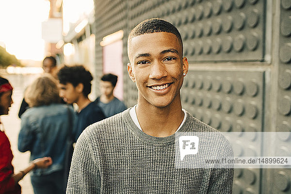 Porträt eines lächelnden Teenagers mit Freunden im Hintergrund auf der Straße