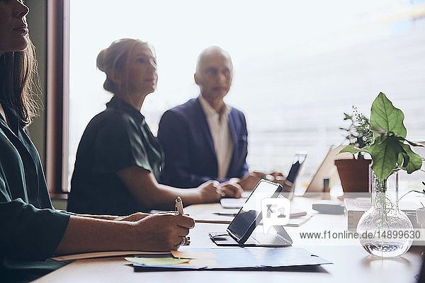 Business colleagues sitting at conference table in board room during meeting
