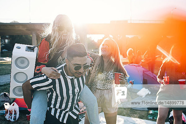 Mann nimmt Freundin mit Sprecher huckepack  während er am Musikfestival teil