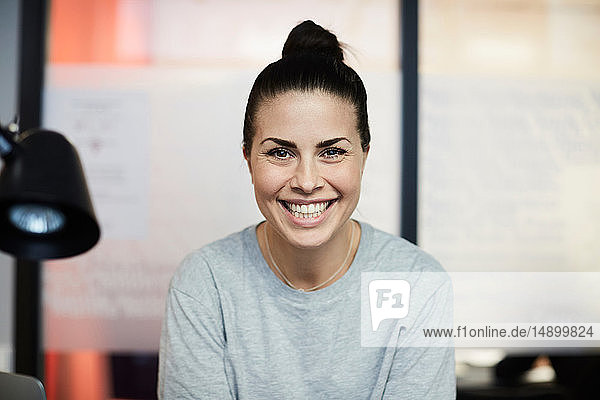 Porträt einer lächelnden Geschäftsfrau  die in einem kreativen Büro sitzt