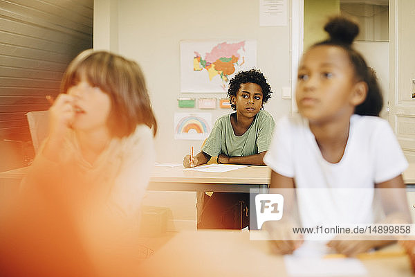 Male and female students sitting at desk in classroom