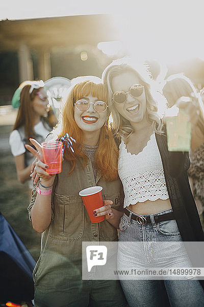 Porträt glücklicher Freunde  die am sonnigen Tag beim Musikfestival einen Drink genießen