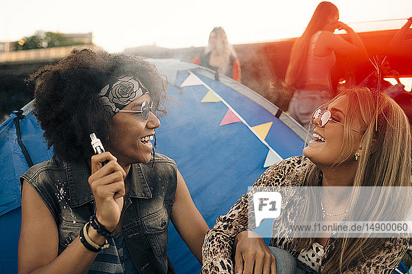 Smiling man with eletronic ciagrette looking at woman against tent