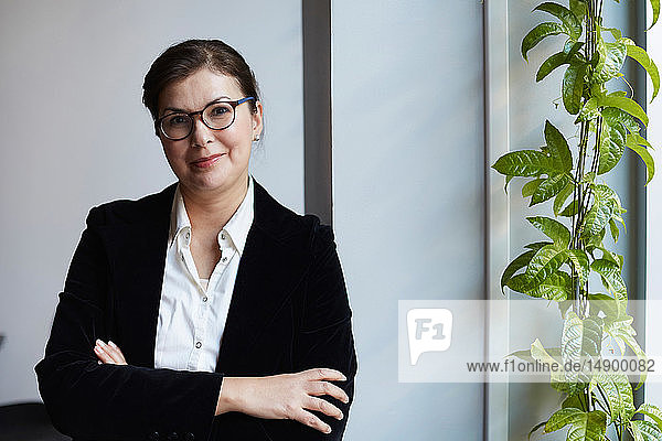 Portrait of smiling mature businesswoman leaning on wall in office