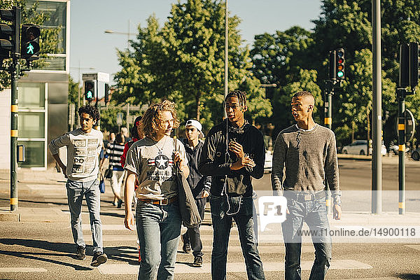 Male friends crossing road in city