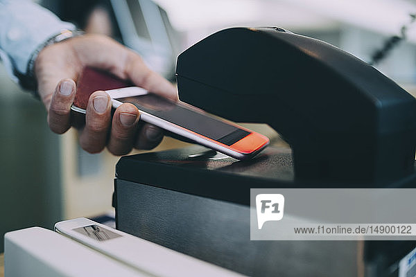 Abgetrennte Hände eines Geschäftsmannes scannen Ticket mit einem Smartphone am Flughafen-Check-in-Schalter