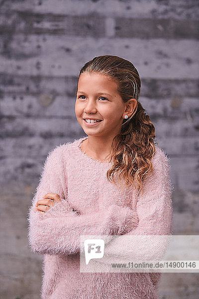 Smiling girl with arms crossed looking away while standing outdoors