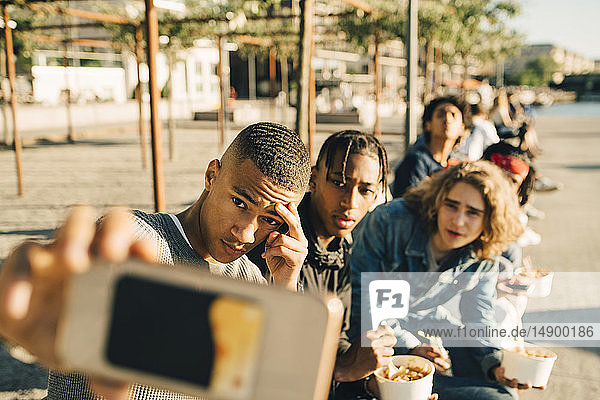 Männliche Freunde  die sich während des Essens egoistisch verhalten  gehen in der Stadt auf der Straße essen
