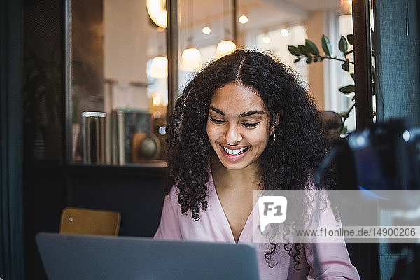Lächelnde junge Geschäftsfrau benutzt Laptop im Kreativbüro