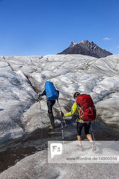 Couple backpacking across the Root Glacier with crampons on during summer towards Donoho Peak  Wrangell Mountains  Wrangell-St. Elias National Park  South-central Alaska; Kennicott  Alaska  United States of America
