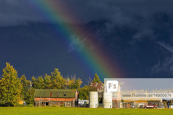 Ein Regenbogen endet über einer Farm  Mat-Su Valley  Süd-Zentral-Alaska; Palmer  Alaska  Vereinigte Staaten von Amerika