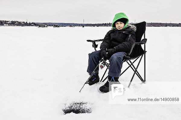 Junge wartet geduldig auf einen Biss beim Eisfischen am Wabamun Lake; Wabamun  Alberta  Kanada