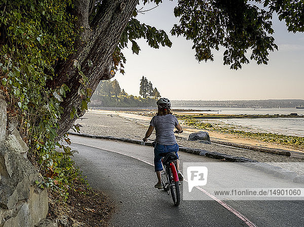 Eine Frau fährt mit dem Fahrrad auf dem Stanley Park Seawall Trail; Vancouver  British Columbia  Kanada