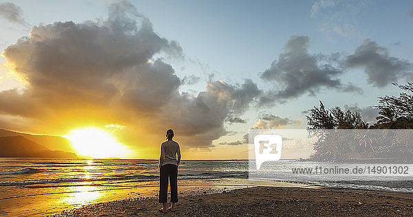 Frau steht am Strand bei Sonnenuntergang; Kauai  Hawaii  Vereinigte Staaten von Amerika