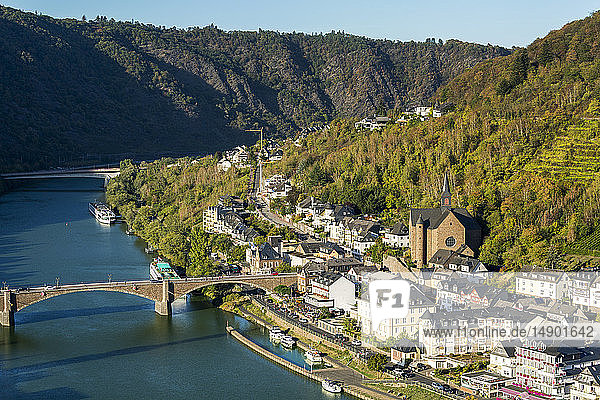 Hohe Ansicht eines Flussdorfs mit Steinkirche und steilen Hängen mit Steinbrückenübergang; Cochem  Deutschland