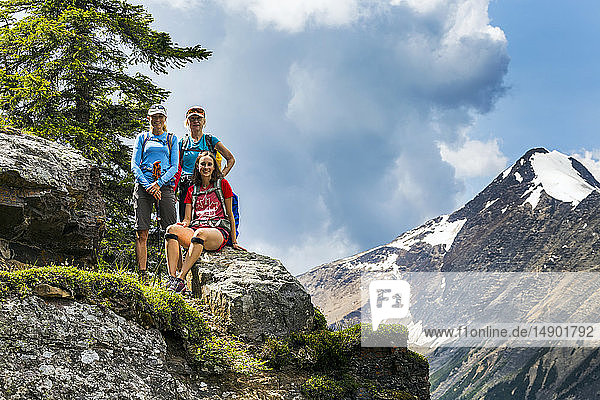 Drei weibliche Wanderer auf einem Bergfelsen mit Berg und blauem Himmel im Hintergrund; British Columbia  Kanada