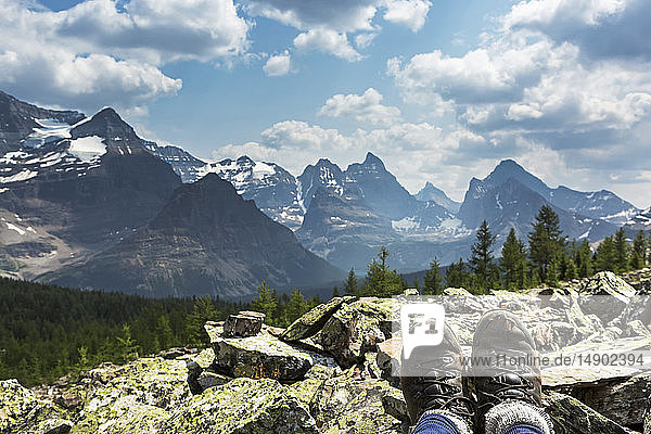 Hiker's boots resting on a rocks with valley and mountain range in the background; British Columbia  Canada