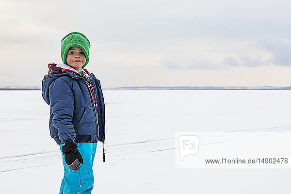 A young boy walking on a frozen lake while ice fishing during a winter family outing; Wabamun  Alberta  Canada.