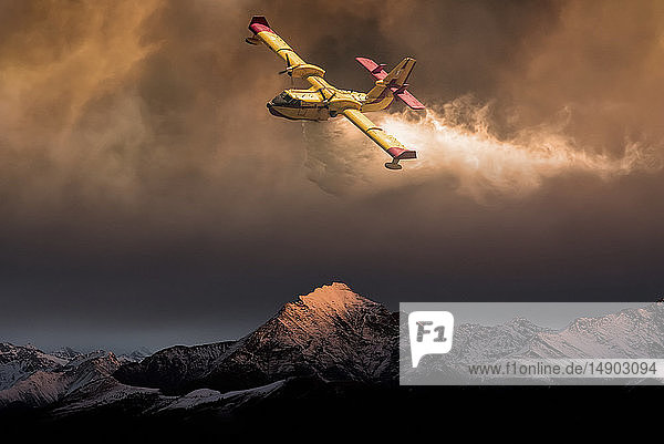 An aircraft dropping water on a forest fire in the mountains below composite image