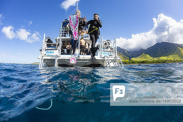 Divers step off a dive boat into the Pacific Ocean out from Ukumehame; Ukumehame  Maui  Hawaii  United States of America