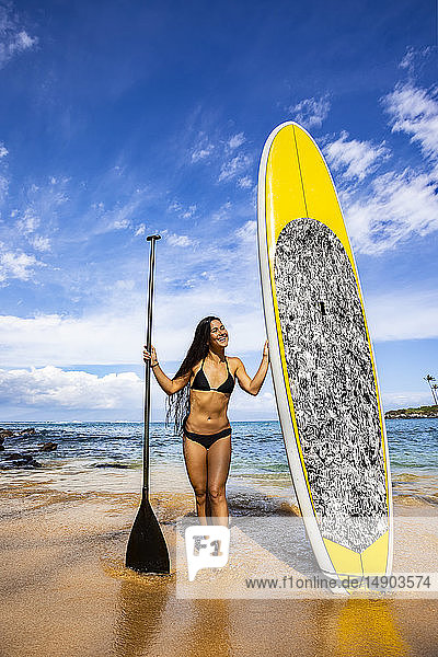 Young woman in bikini with stand up paddle board and paddle on the beach in Kapalua Bay; Maui  Hawaii  United States of America
