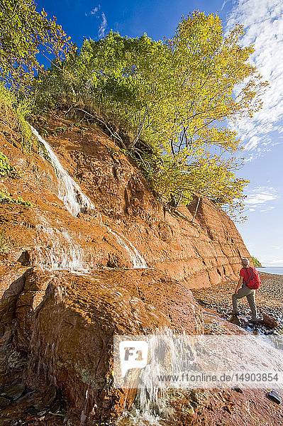Hiking at low tide beside the sandstone cliffs  Cape Blomidon Provincial Park in the Minas Basin  Bay of Fundy; Nova Scotia  Canada