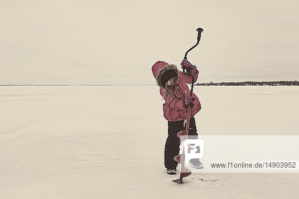 Junges Mädchen versucht erfolglos  ein Loch in das Eis des zugefrorenen Wabamun-Sees zu bohren: Wabamun  Alberta  Kanada