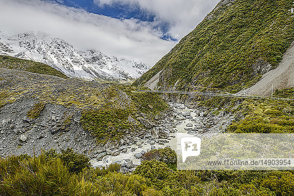 Snowy mountains and hanging bridge along the Hooker Valley Track Mount Cook National Park; South Island New Zealand
