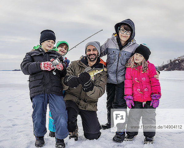Father and four children showing off their catch before releasing it while ice fishing at Lake Wabamun; Wabamun  Alberta  Canada