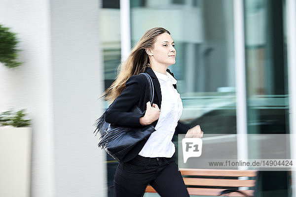 Junge Geschäftsfrau läuft auf dem Bürgersteig